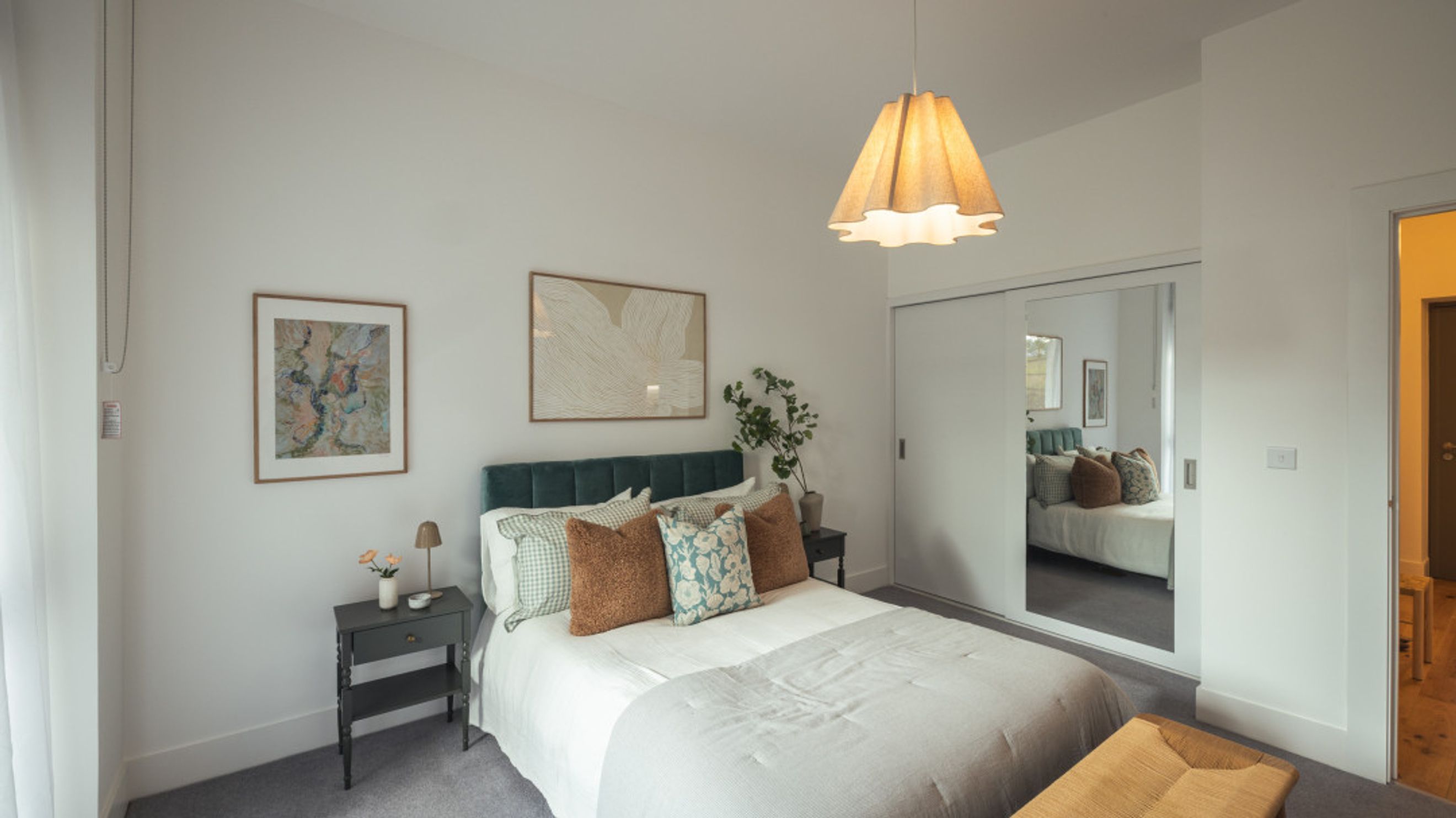 A bedroom with a bed, nightstand, and a mirrored wardrobe.