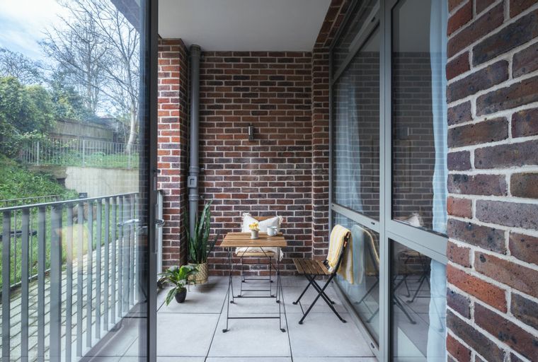 A balcony with a small table, two chairs, and plants.