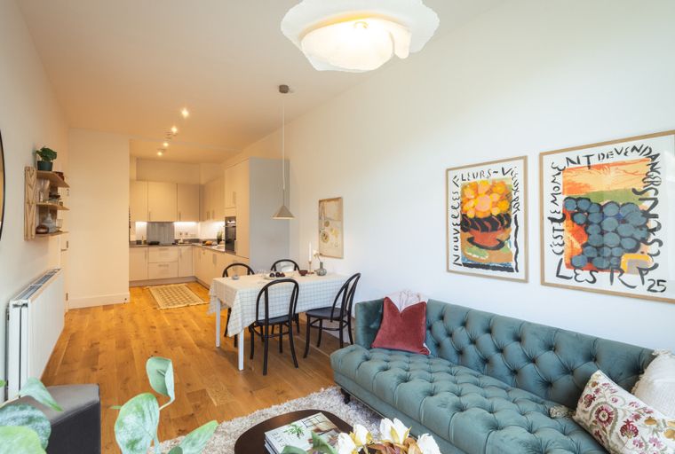 A living room and kitchen area with a sofa, dining table, and kitchen cabinets.