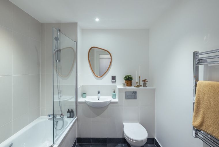 A bathroom with a bathtub, shower, sink, toilet, and mirror.