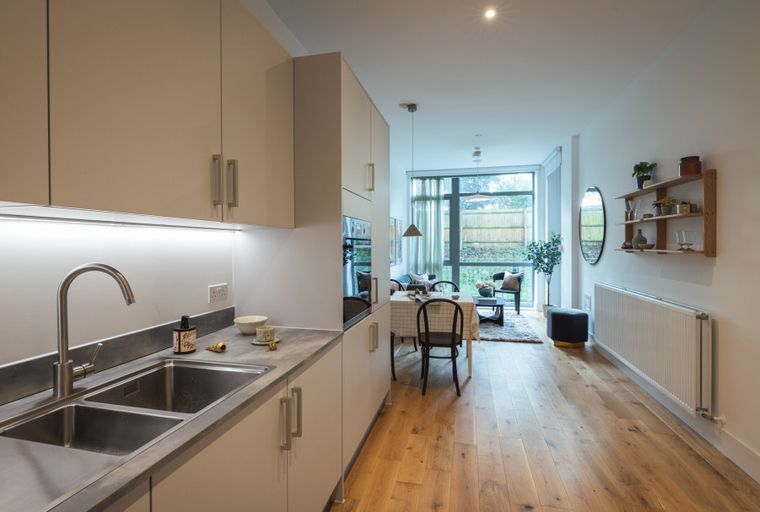 A modern kitchen and living area with a sink, dining table, and large windows.