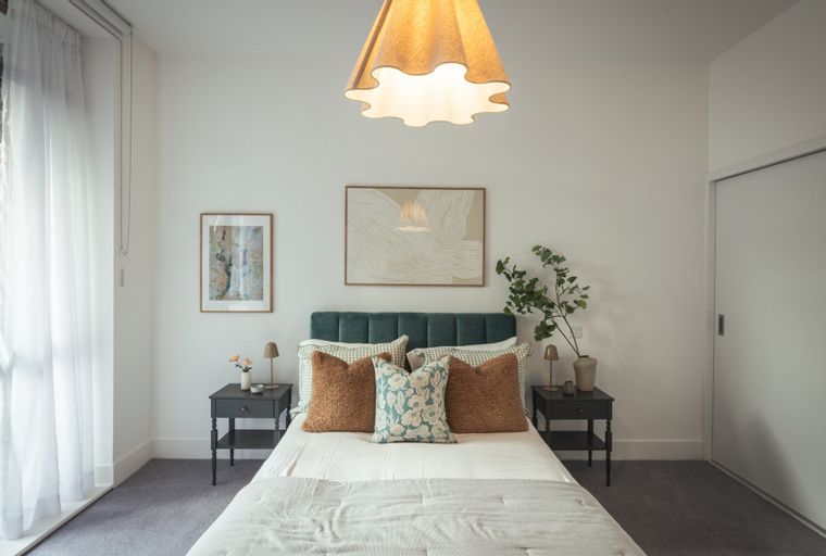 A bedroom with a bed, bedside tables, and artwork.
