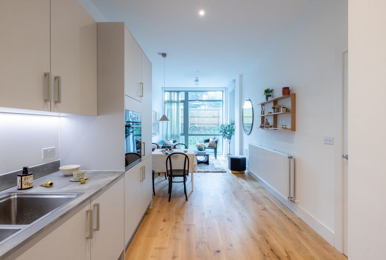A kitchen and living area with a dining table and chairs.