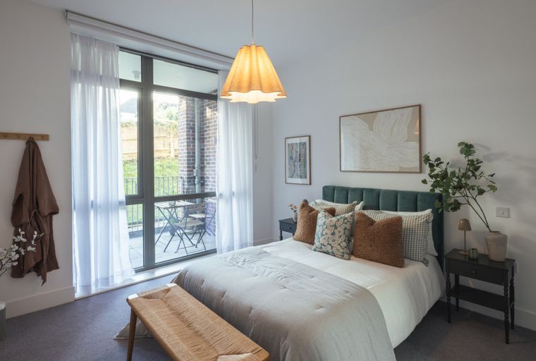 A bedroom with a bed, nightstands, and a large window.
