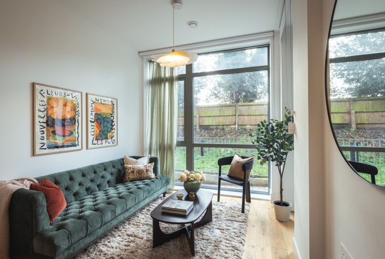 A living room with a green sofa, coffee table, and two framed artworks on the wall.