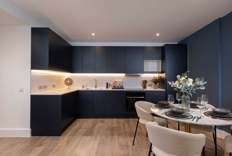 A modern kitchen and dining area with dark navy cabinets, a marble-top table, and chairs.