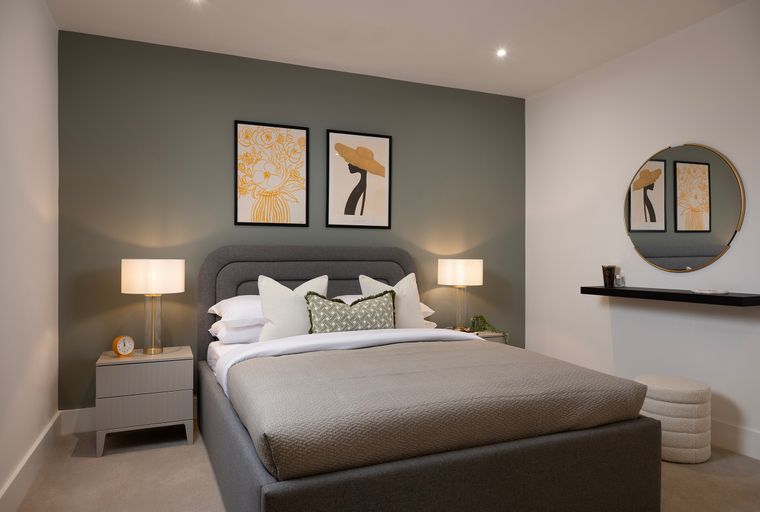 A bedroom with a bed, bedside tables, and artwork on the wall.
