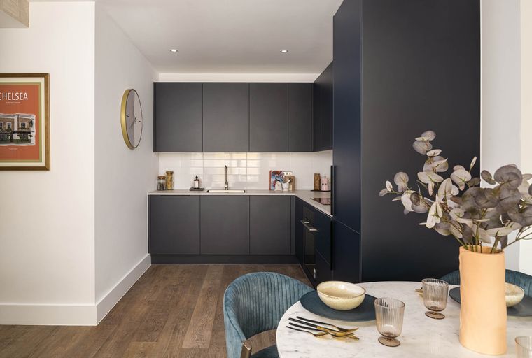 A modern kitchen and dining area with dark cabinets, a white tiled backsplash, and a round dining table.