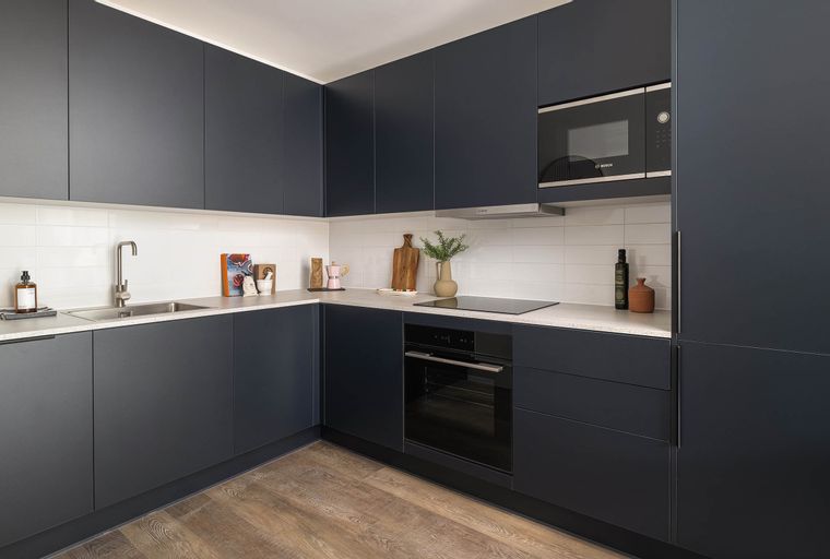 A modern kitchen with dark cabinets, a sink, an oven, and a microwave.