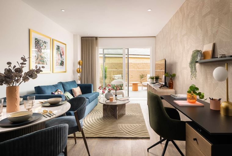A living room and dining area with a blue sofa, dining table, and a desk.