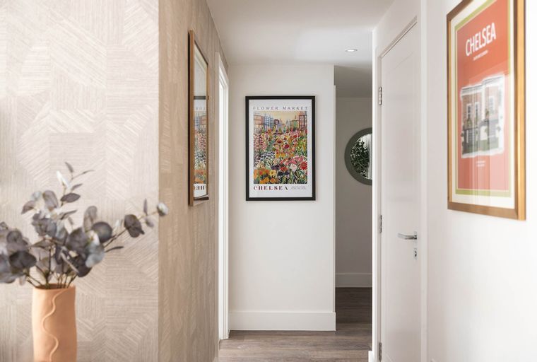 A hallway with two framed pictures on the wall and a vase of flowers.