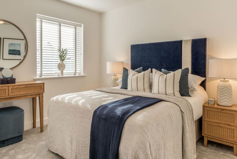 A bedroom with a bed, bedside tables, and a vanity.
