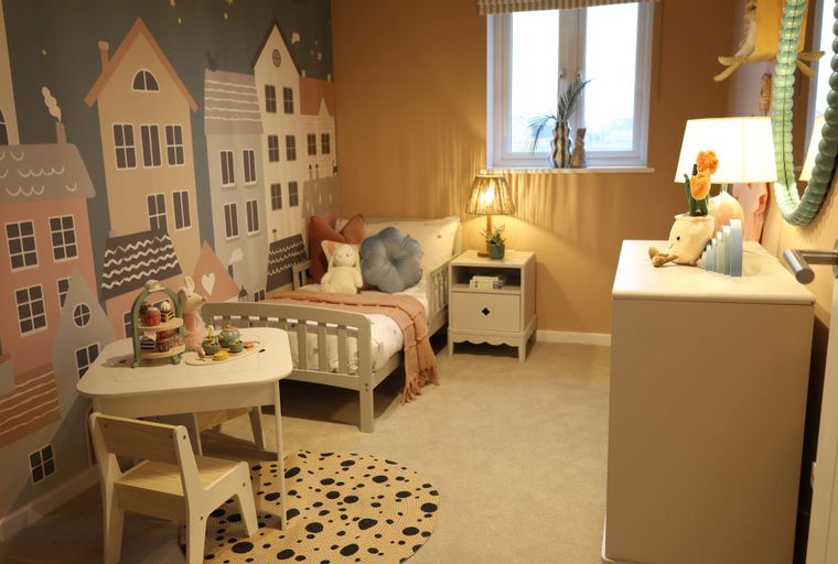 A children's bedroom with a mural, bed, and a small table.