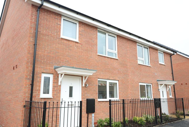 A row of modern red brick houses with white windows and doors.