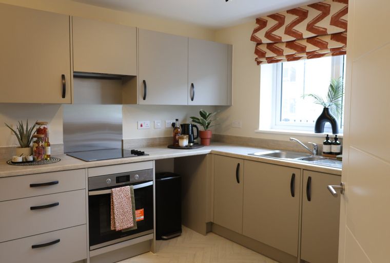 A kitchen with cabinets, a hob, an oven, and a sink.