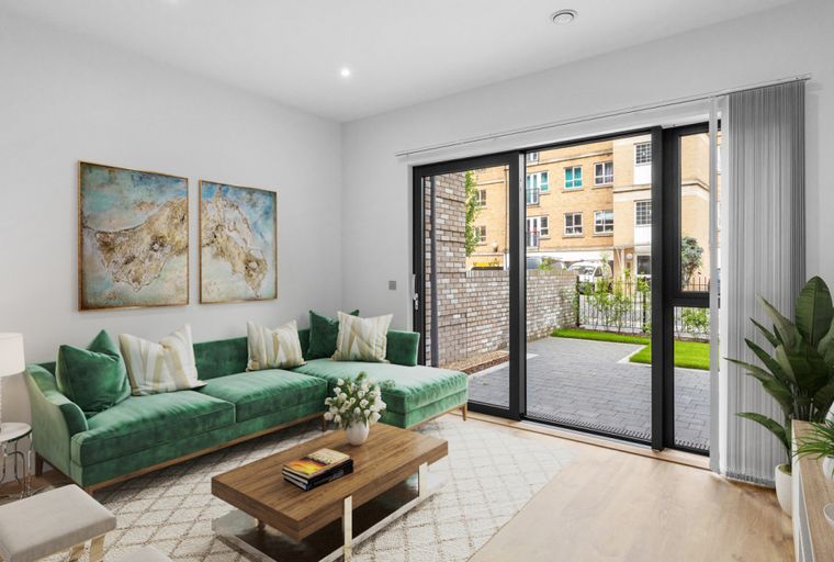 A living room with a green sectional sofa, coffee table, and large sliding glass doors leading to an outdoor patio.