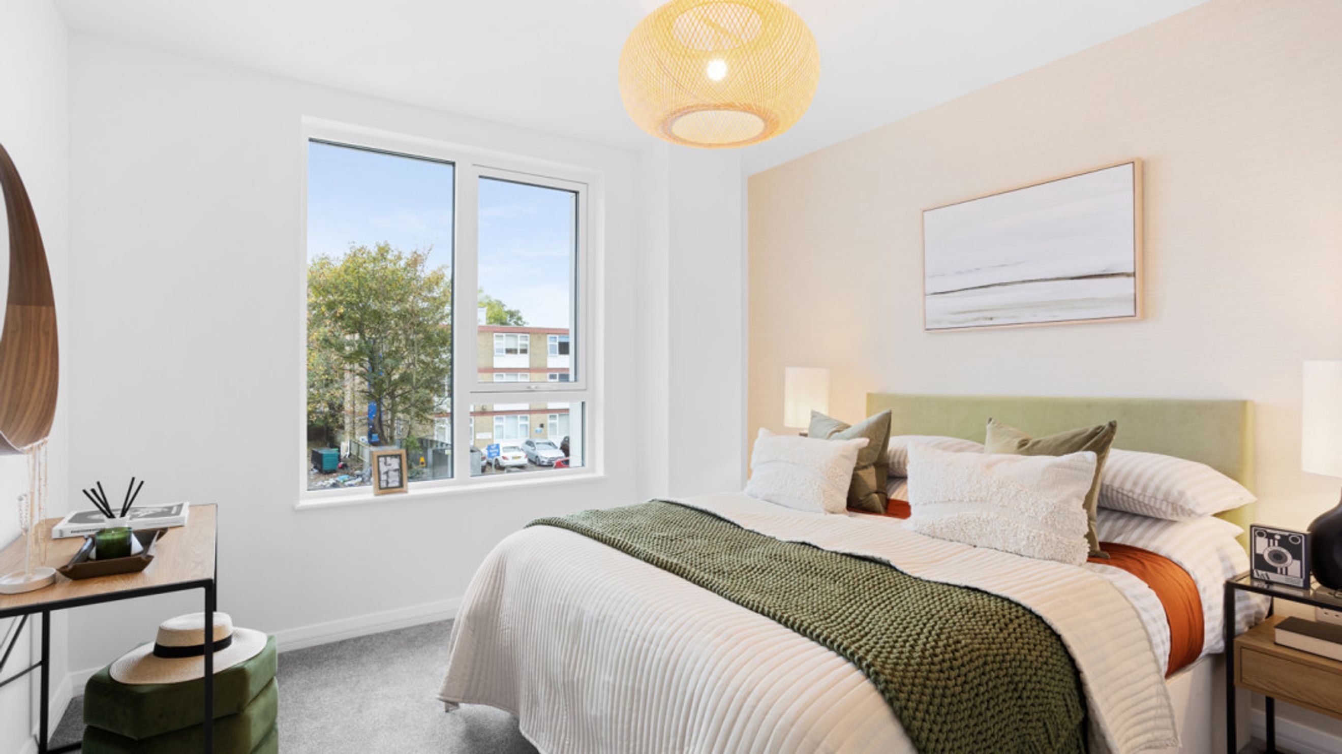 A bedroom with a bed, pillows, a headboard, a window, and a vanity.