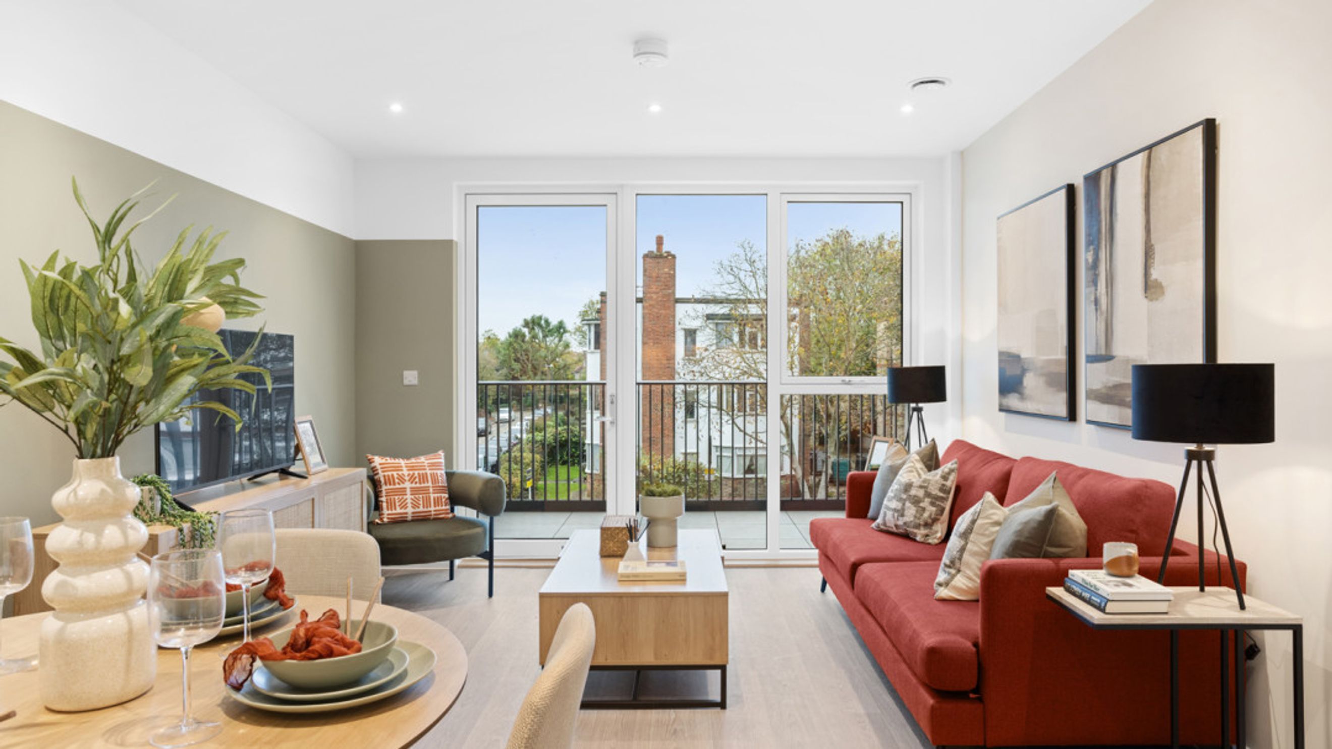 A living room with a red sofa, coffee table, and large windows.