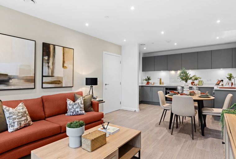 A living room and kitchen area with a sofa, dining table, and kitchen cabinets.