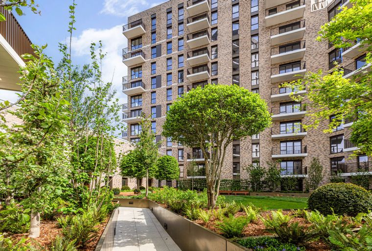 A courtyard with a modern apartment building and lush landscaping.