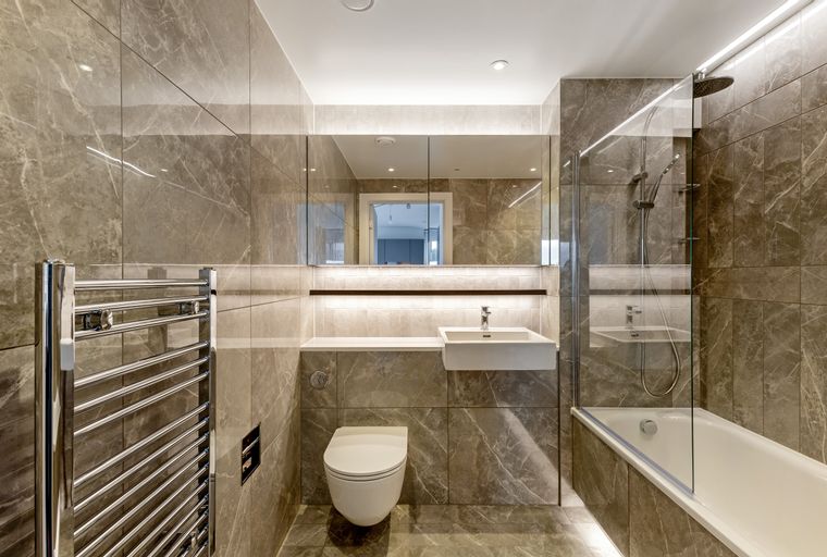 A modern bathroom with a toilet, sink, bathtub, and a heated towel rail.