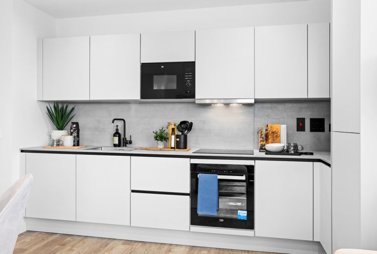 A modern kitchen with white cabinets, a black faucet, and integrated appliances.