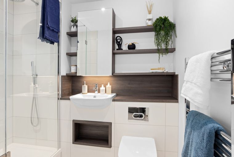 A modern bathroom with a shower, sink, toilet, and shelves.