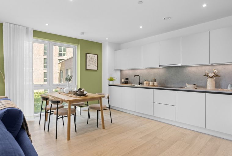A dining area and kitchen with white cabinets and a wooden table.