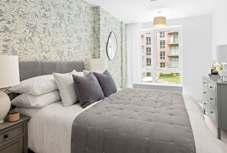 A bedroom with a bed, pillows, a nightstand, and a dresser.