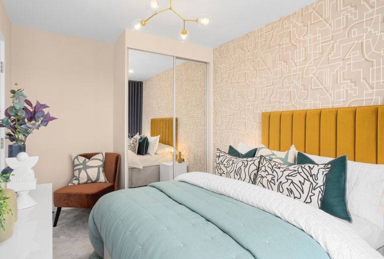 A bedroom with a bed, headboard, pillows, and a chair.