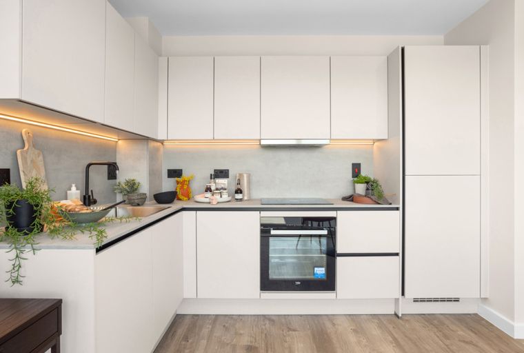 A modern kitchen with white cabinets, a black faucet, and integrated appliances.