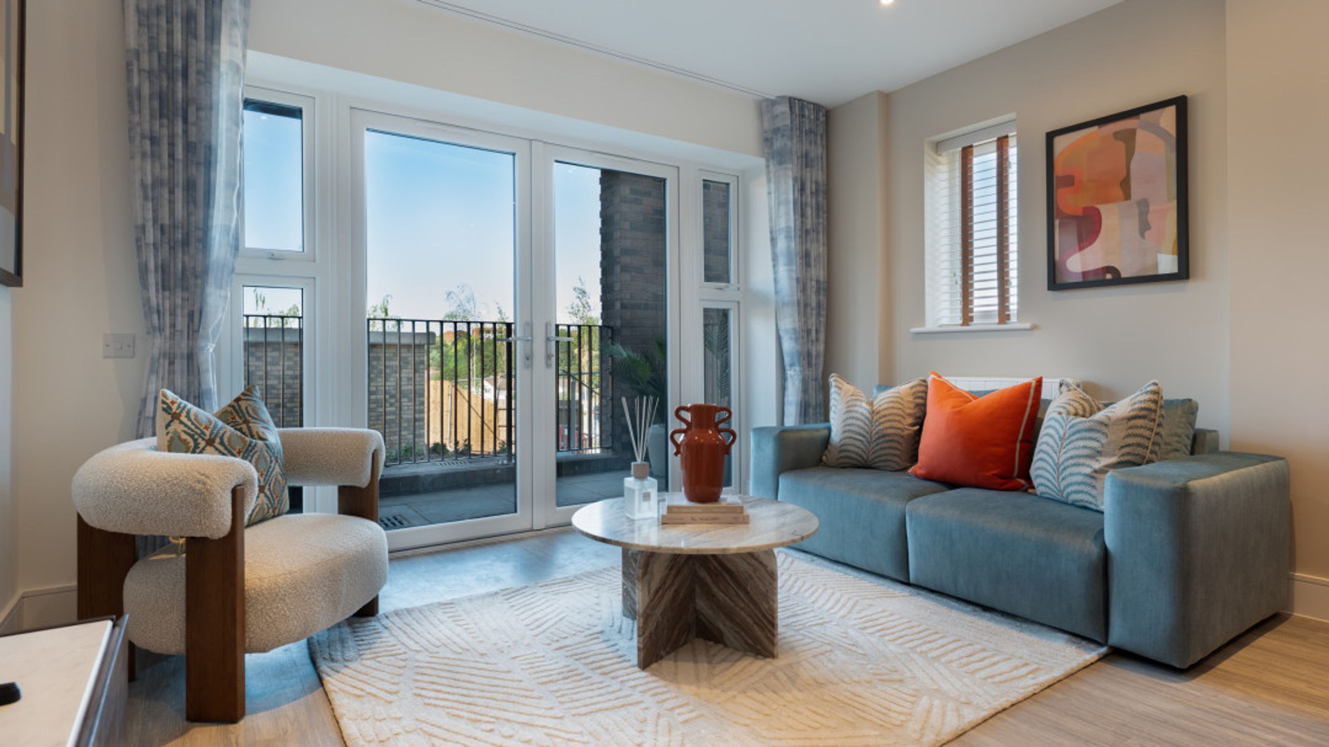 A living room with a sofa, armchair, coffee table, and balcony doors.
