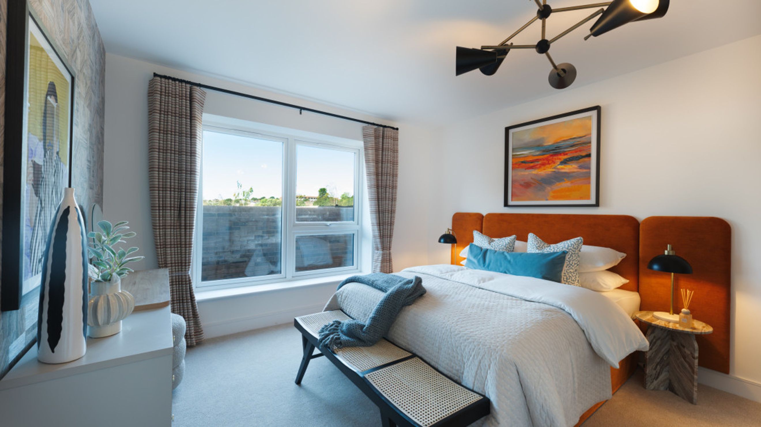 A bedroom with a bed, headboard, bedside table, bench, and window.