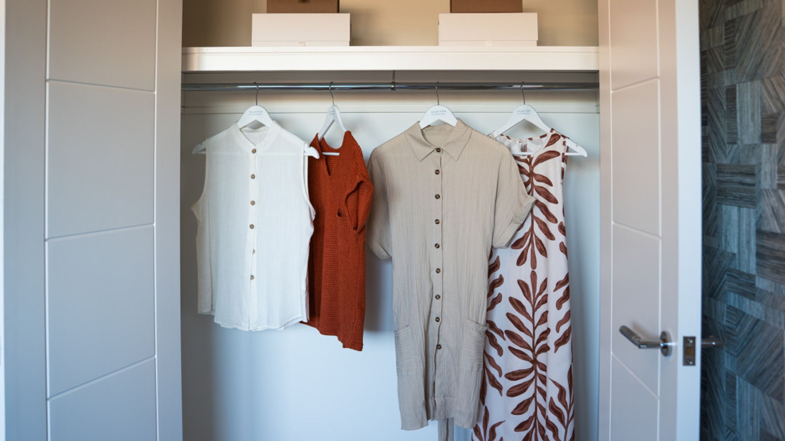 A closet with clothes hanging on a rod.