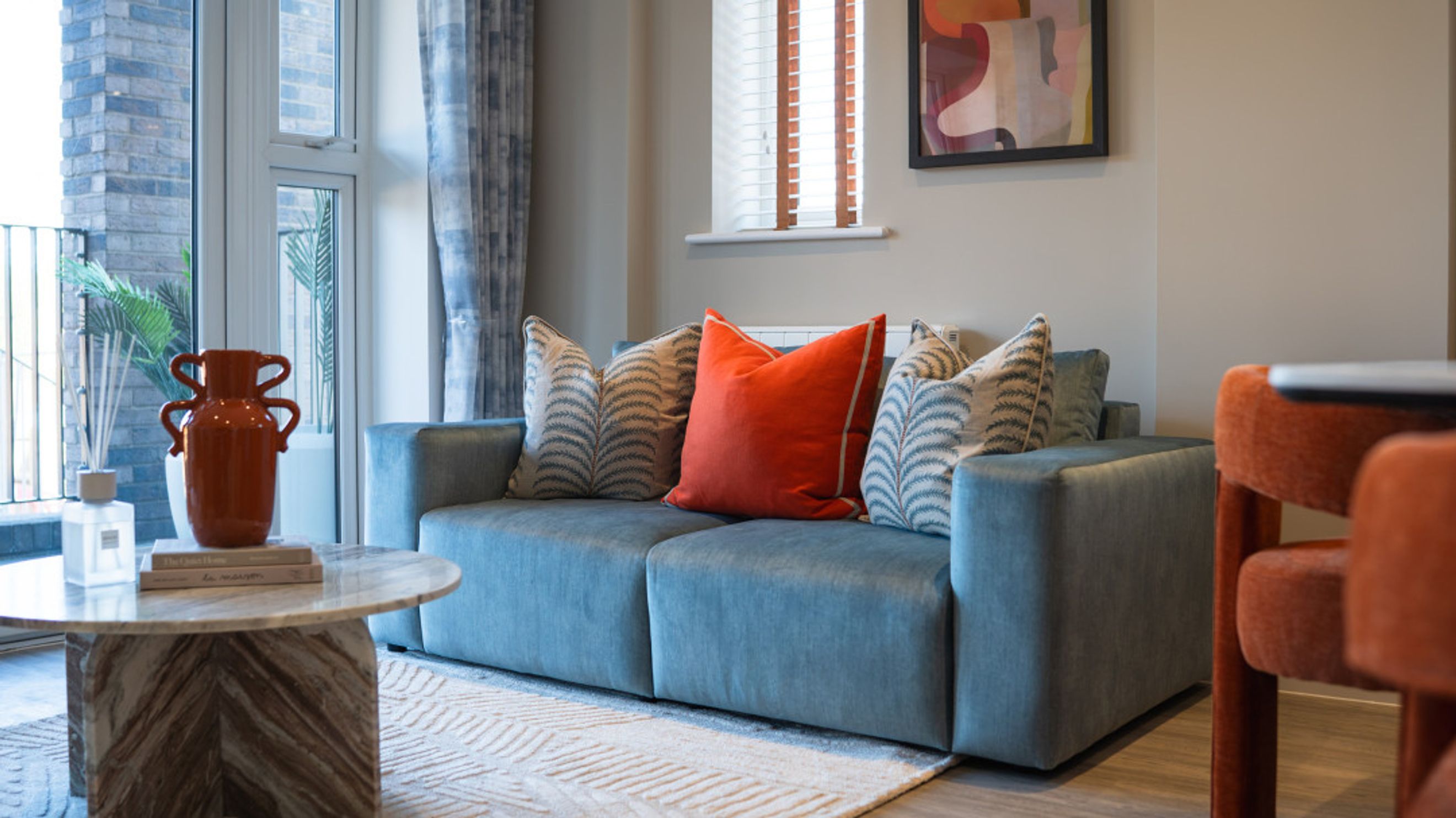 A living room with a blue sofa, decorative pillows, and a marble coffee table.