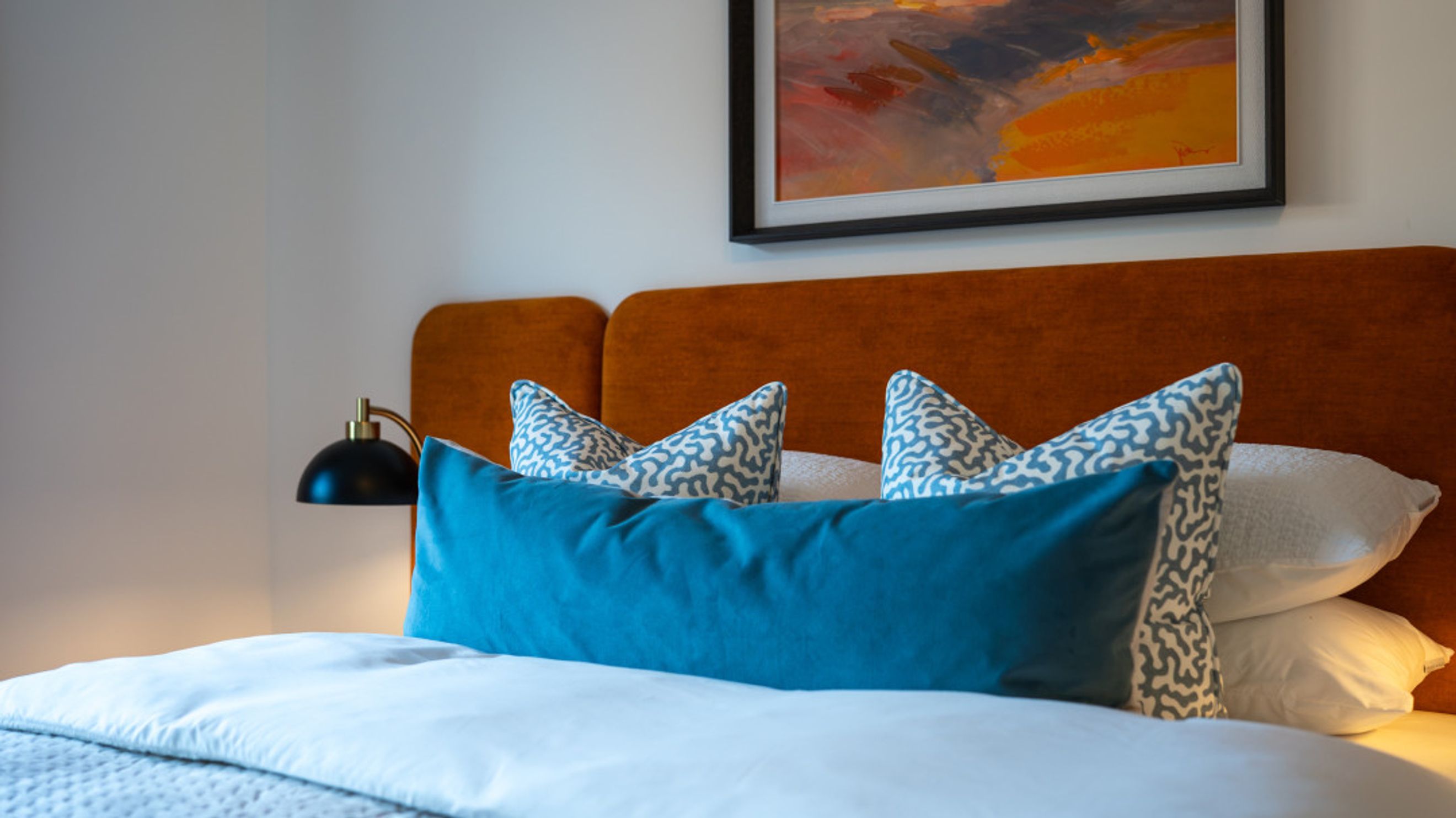 A bedroom with a bed, pillows, and a headboard.