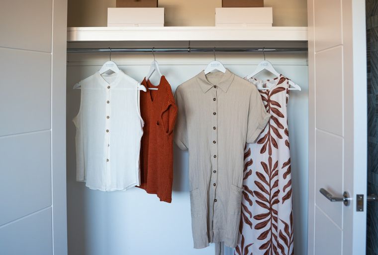 A closet with clothes hanging on a rod.