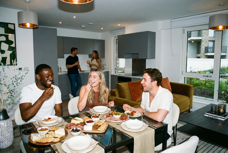 A group of friends enjoying a charcuterie board and drinks around a dining table in a modern apartment.
