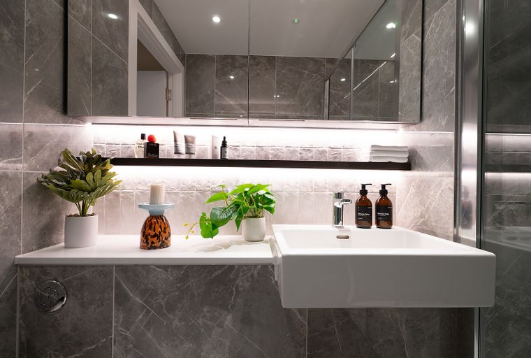 A modern bathroom vanity with a sink, faucet, soap dispensers, and decorative items.