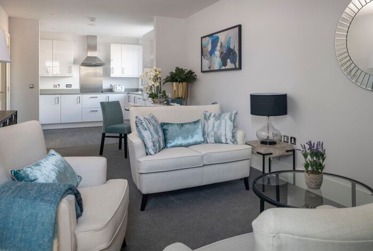A living room and kitchen area with sofas, chairs, and kitchen cabinets.