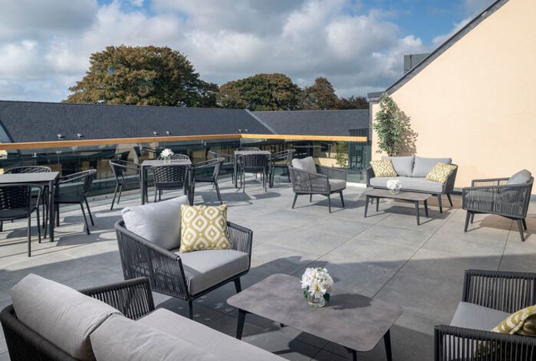 A rooftop terrace with outdoor furniture and tables.