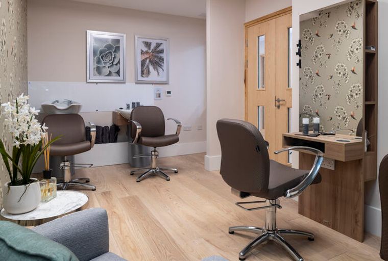 A salon with styling chairs, a wash basin, and a mirror.