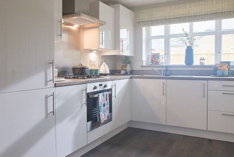 A modern kitchen with white cabinets, a gas hob, and a large window.