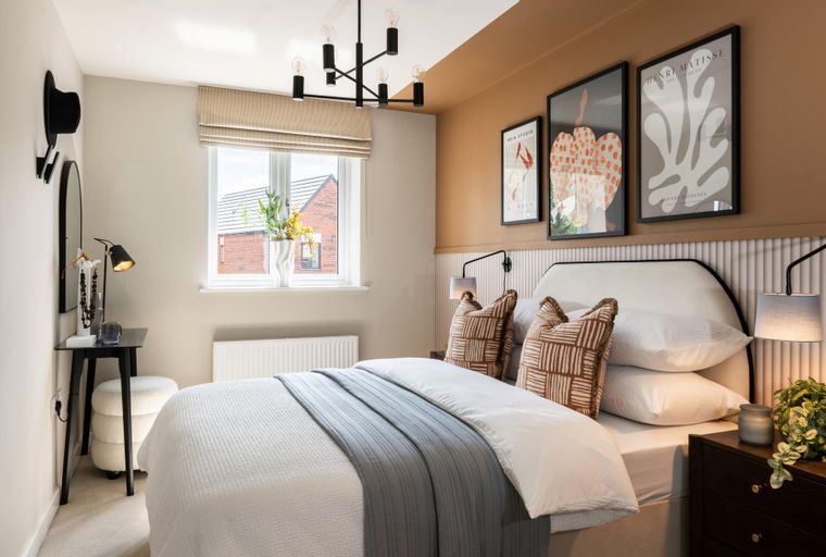 A bedroom with a bed, pillows, and artwork.
