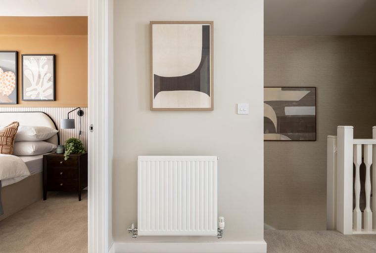 A bedroom with a bed, bedside table, and artwork in the hallway.