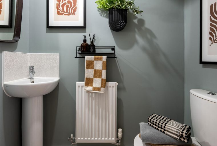A bathroom with a corner sink, radiator, and toilet.