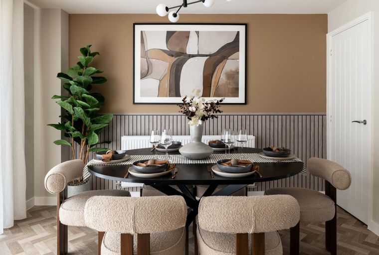 A dining room with a round table, chairs, and a large abstract painting on the wall.
