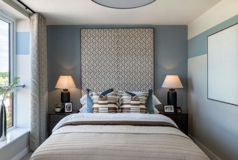 A bedroom with a bed, headboard, bedside tables, and lamps.