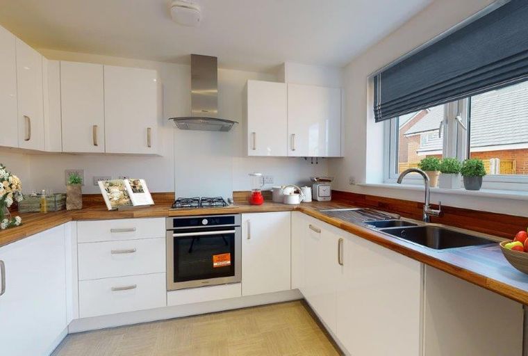 A modern kitchen with white cabinets, wooden countertops, and a sink.