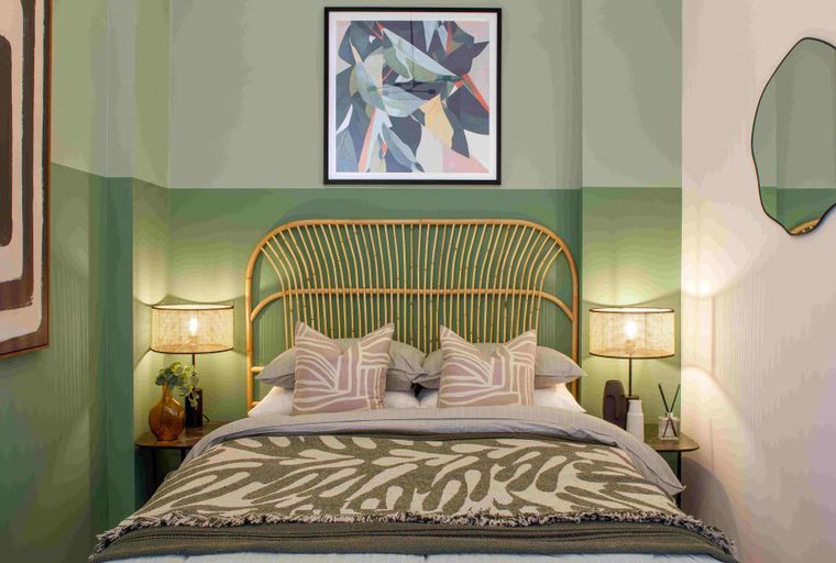 A bedroom with a bed, headboard, pillows, and lamps.